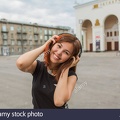 beautiful-asian-girl-listening-to-music-with-headphones-on-the-street-H2AHRN.jpg