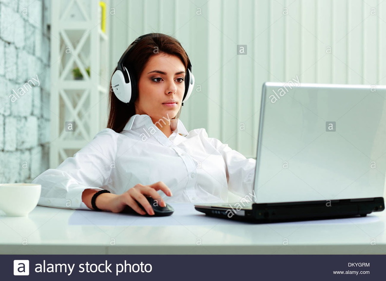young-businesswoman-in-headphones-working-on-a-laptop-at-office-DKYGRM.jpg
