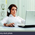 young-businesswoman-in-headphones-working-on-a-laptop-at-office-DKYGRM