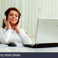 young-beautiful-businesswoman-listening-music-in-headphones-at-office-DK6M5C
