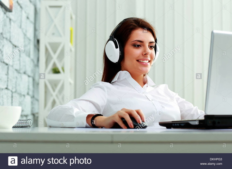 young-businesswoman-in-headphones-working-on-a-laptop-at-office-DKHPG3.jpg