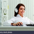 young-businesswoman-in-headphones-working-on-a-laptop-at-office-DKHPG3