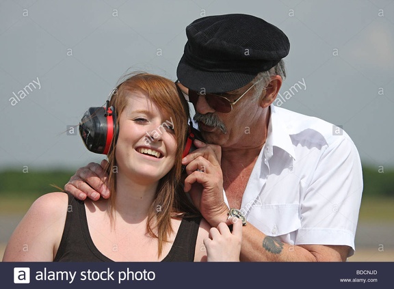 a-teenage-girl-wearing-ear-defenders-at-an-air-show-with-her-grandfather-BDCNJD