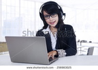 stock-photo-young-beautiful-woman-working-with-laptop-computer-and-headset-in-the-office-256983025