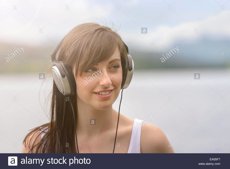 young-woman-wearing-headphones-at-lakeside-under-bright-sunlight-EA05F7