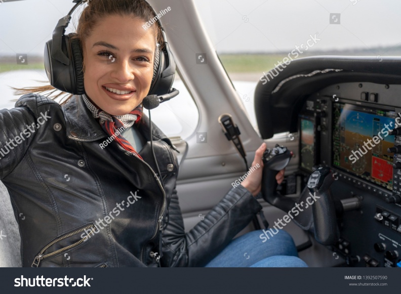 stock-photo-smiling-young-woman-pilot-with-headset-sitting-in-airplane-cockpit-portrait-of-attractive-young-1392507590.jpg