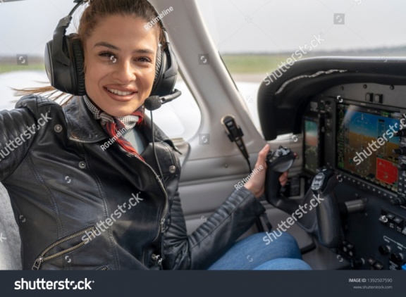 stock-photo-smiling-young-woman-pilot-with-headset-sitting-in-airplane-cockpit-portrait-of-attractive-young-1392507590