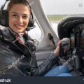 stock-photo-smiling-young-woman-pilot-with-headset-sitting-in-airplane-cockpit-portrait-of-attractive-young-1392507590