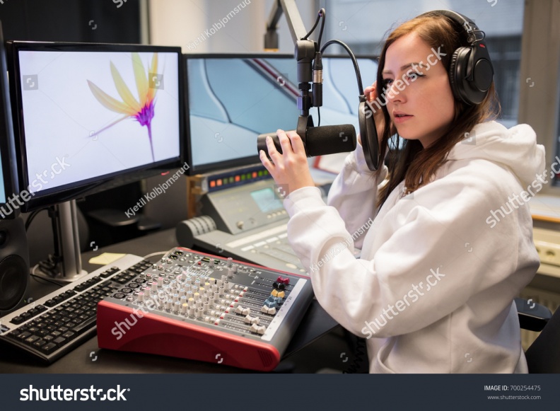 stock-photo-host-adjusting-headphones-and-microphone-at-table-in-radio-studi-700254475