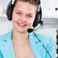 89695007-office-worker-woman-is-working-at-a-computer-and-talking-by-headset-with-client-in-the-office-