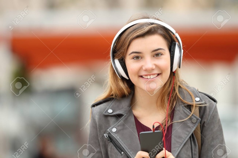71234198-front-view-of-a-happy-young-adult-girl-listening-music-on-line-with-headphones-and-looking-at-you-in.jpg