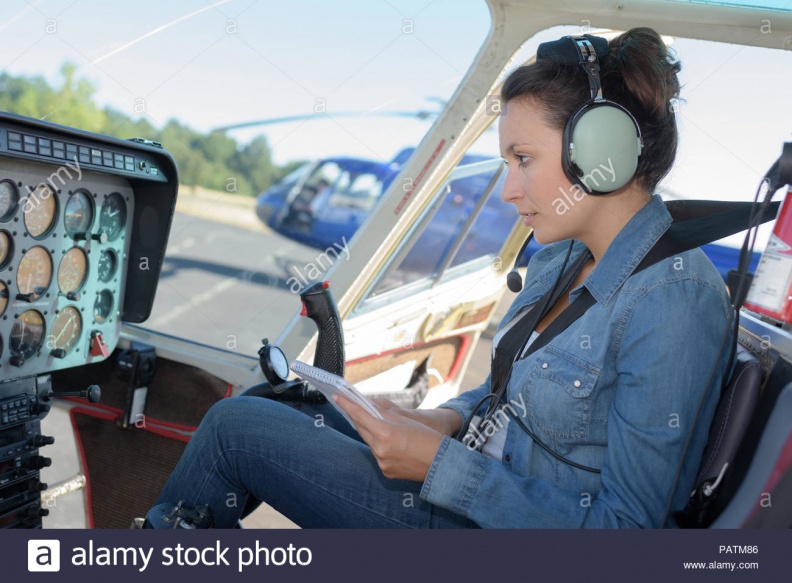 female-helicopter-pilot-reading-a-manual-while-sitting-in-cockpit-PATM86.jpg
