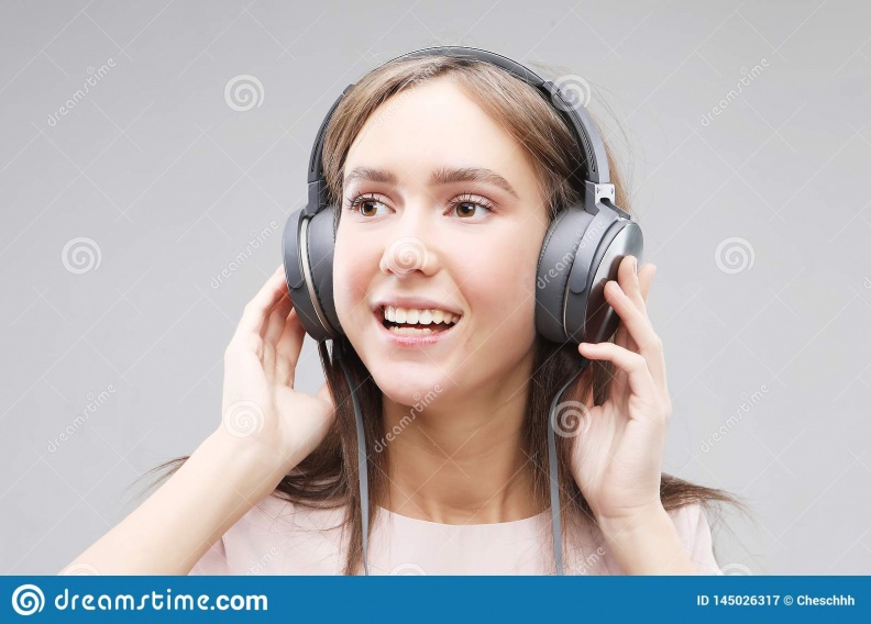 young-woman-headphones-listening-to-music-beautiful-standing-grey-background-pink-t-shirt-145026317
