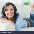 woman-listening-music-looking-happy-on-sofa-X4JGDM