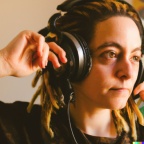 A young adult caucasian woman with blonde dreadlocks wearing large black vintage headphones (2)