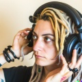 A young adult caucasian woman with blonde dreadlocks wearing large black vintage headphones (3)