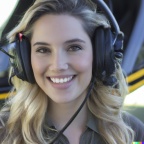 A high resolution photo of a cute, smiling young blonde woman wearing a large helicopter headset, detailed, realistic (5)