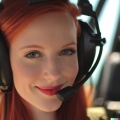 A high resolution photo of a cute, smiling young redheaded Caucasian woman wearing a large helicopter headset, detailed, realistic (8)