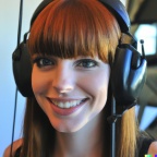 A high resolution photo of a skinny, cute, smiling young redheaded Caucasian woman with bangs wearing a large helicopter headset, detailed, realistic (4)