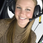 A high resolution photo of an attractive smiling young woman wearing a large helicopter headset, detailed, realistic (2)