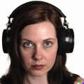 A high resolution, hyperrealistic photograph of a gorgeous young woman with a mesmerised look in her eyes, wearing large black vintage headphones, iso