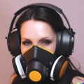 A wide-shot photo of a gorgeous smiling young woman wearing large black vintage headphones over her ears, and wearing a transparent oxygen mask over h.jpg