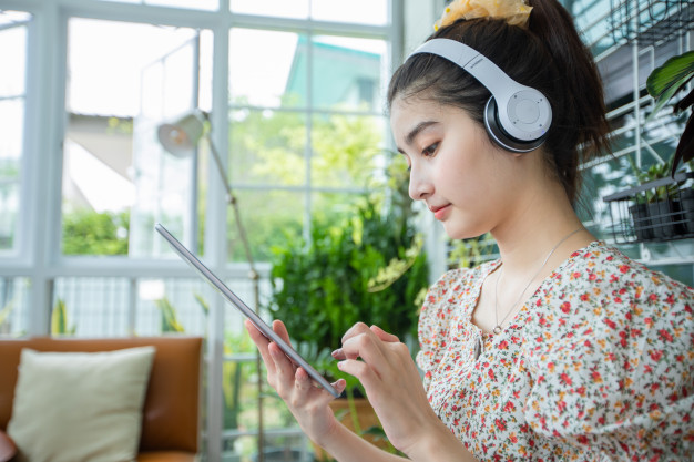 asian-women-wearing-headphones-using-mobile-phone-digital-tablet-listening-music-singing-relaxing-day-home_33718-1773.jpg